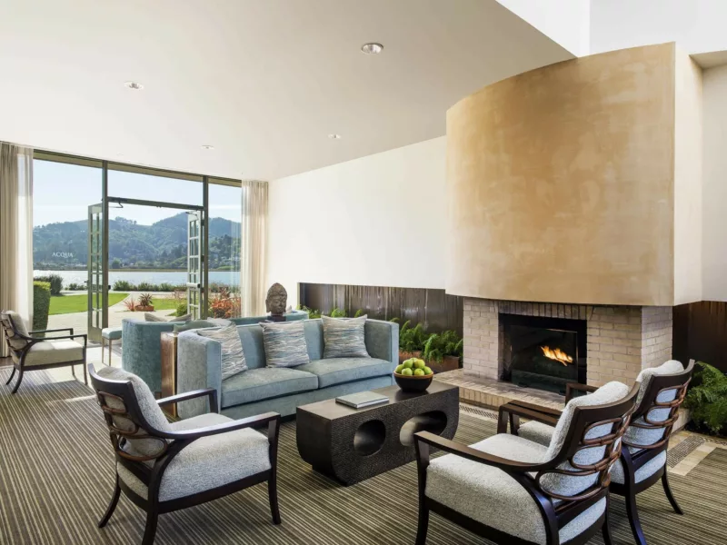main seating group in lobby in front of fireplace with bay and hill views in the background